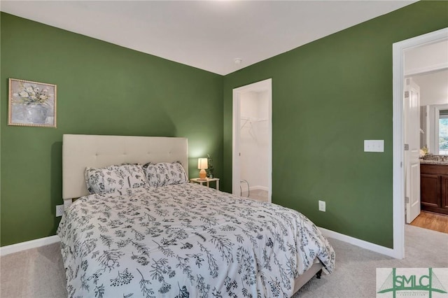 carpeted bedroom with ensuite bath, a spacious closet, and a closet