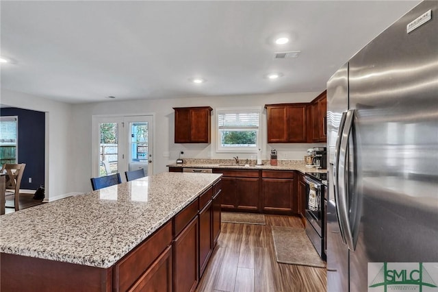 kitchen with plenty of natural light, a kitchen island, stainless steel appliances, and dark hardwood / wood-style floors