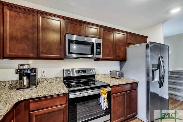 kitchen featuring light stone countertops, light hardwood / wood-style floors, and appliances with stainless steel finishes