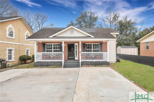 bungalow-style home featuring a front lawn, covered porch, and a storage unit