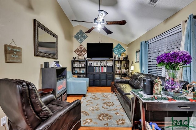 living room featuring ceiling fan, a fireplace, vaulted ceiling, and hardwood / wood-style flooring