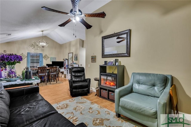 living room featuring wood-type flooring, ceiling fan with notable chandelier, and vaulted ceiling