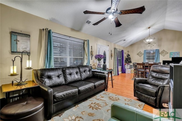 living room with a textured ceiling, hardwood / wood-style floors, ceiling fan with notable chandelier, and lofted ceiling