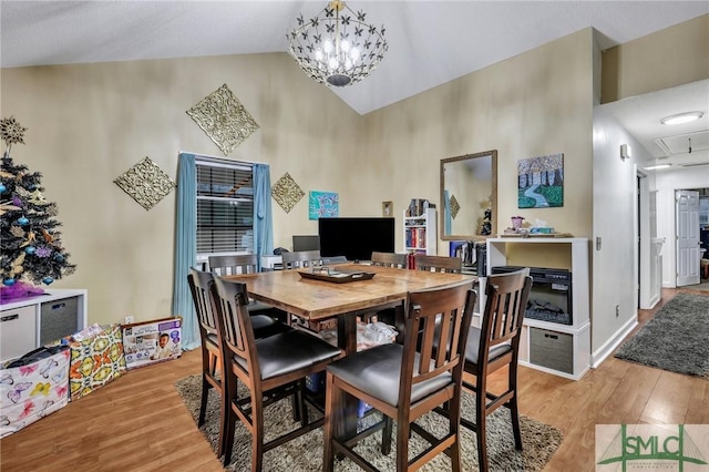 dining area featuring high vaulted ceiling, a notable chandelier, and light wood-type flooring