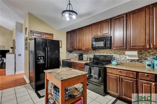 kitchen featuring black appliances, decorative backsplash, light tile patterned floors, and vaulted ceiling