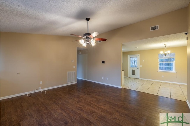 spare room with ceiling fan with notable chandelier, light hardwood / wood-style floors, and a textured ceiling