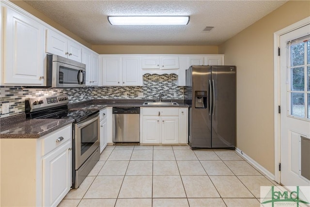 kitchen with decorative backsplash, white cabinetry, sink, and stainless steel appliances