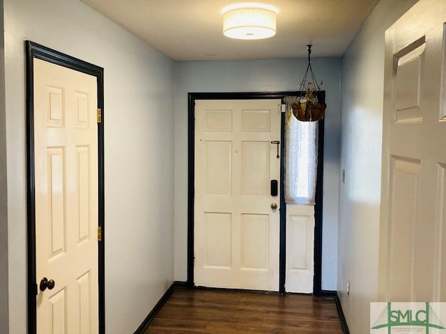 doorway with an inviting chandelier and dark wood-type flooring