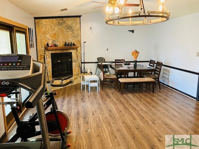 dining area featuring a stone fireplace, hardwood / wood-style floors, and a chandelier