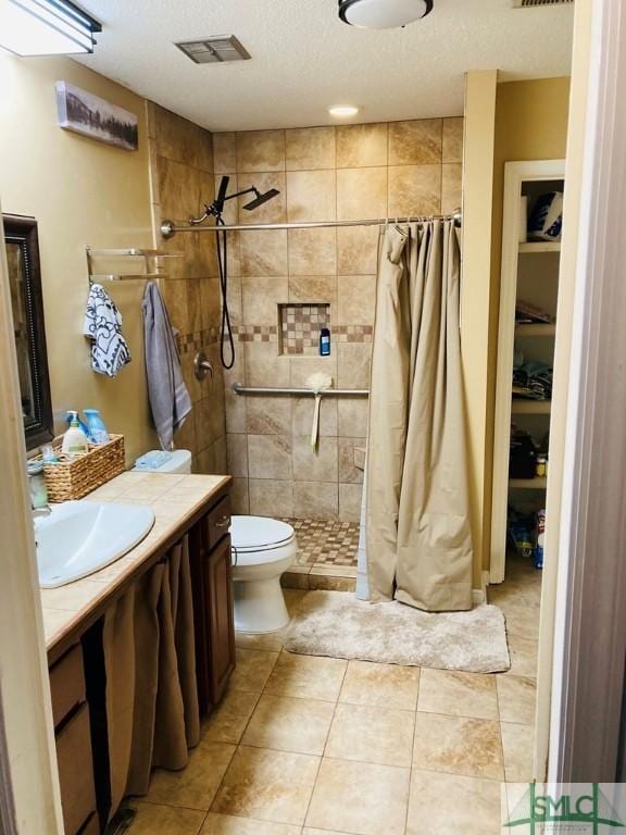 bathroom featuring curtained shower, tile patterned flooring, a textured ceiling, toilet, and vanity