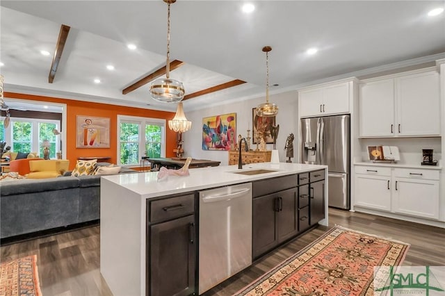 kitchen featuring white cabinetry, sink, hanging light fixtures, stainless steel appliances, and a kitchen island with sink