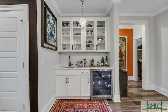 bar featuring pendant lighting, white cabinets, crown molding, sink, and beverage cooler