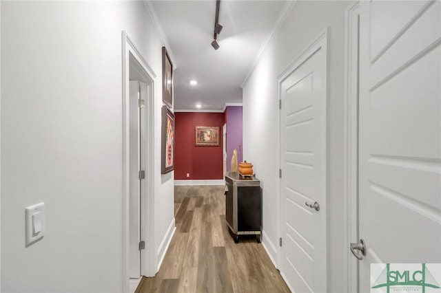 hall featuring wood-type flooring, crown molding, and track lighting