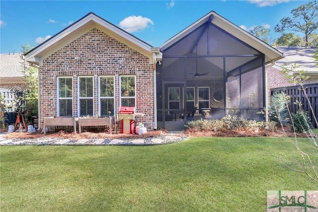 rear view of property with a lawn, a sunroom, and ceiling fan