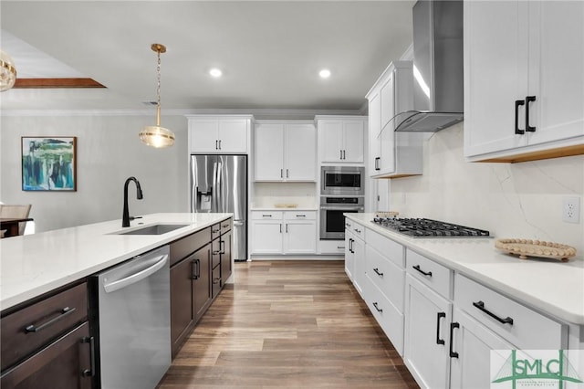 kitchen featuring stainless steel appliances, light countertops, dark brown cabinetry, a sink, and wall chimney exhaust hood