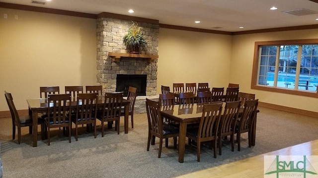 dining room featuring baseboards, visible vents, ornamental molding, a stone fireplace, and recessed lighting