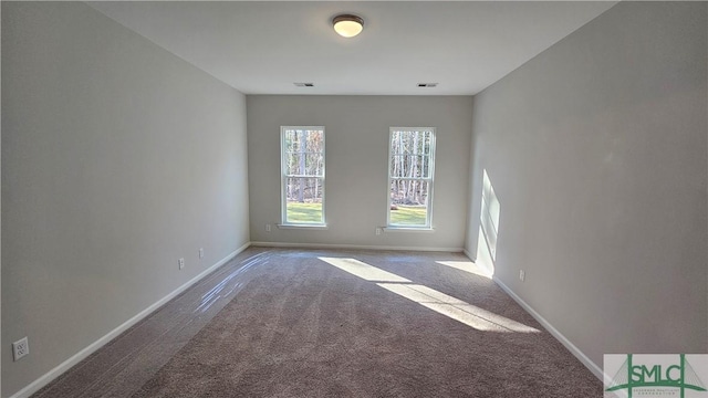 spare room with carpet floors, visible vents, and baseboards