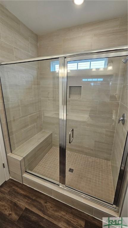 bathroom with a stall shower and wood finished floors