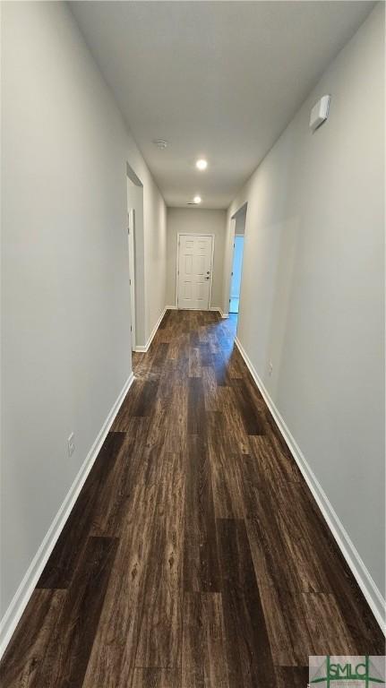 hall with dark wood-type flooring and baseboards