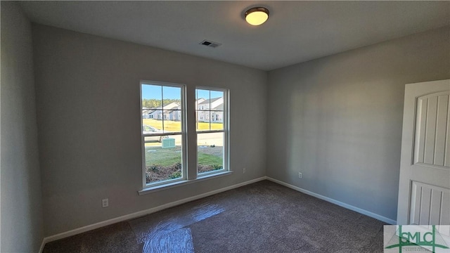 unfurnished room with dark carpet, visible vents, and baseboards