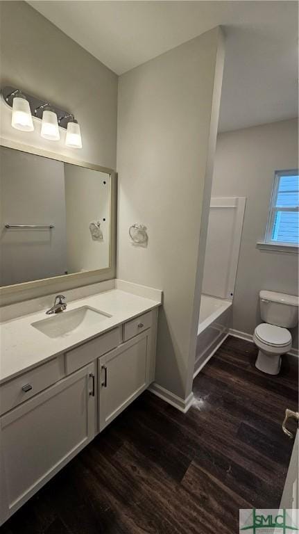 bathroom featuring toilet, wood finished floors, vanity, and baseboards