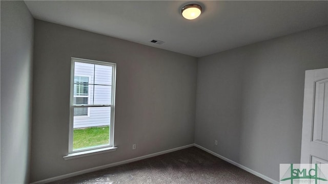 unfurnished room featuring baseboards, visible vents, and dark colored carpet