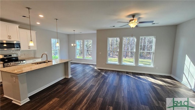 kitchen with tasteful backsplash, light stone counters, stainless steel appliances, white cabinetry, and a sink