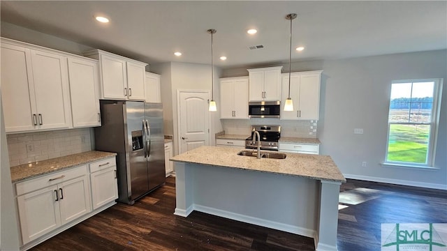 kitchen featuring white cabinets, a center island with sink, stainless steel appliances, and dark wood finished floors