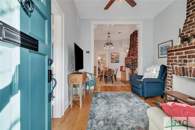 living room featuring light wood-type flooring and ceiling fan with notable chandelier