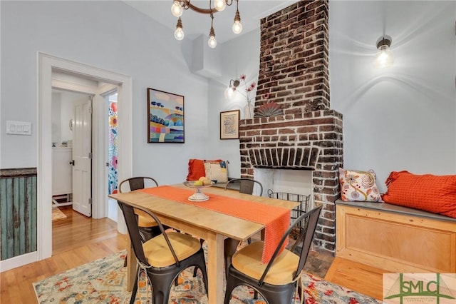 dining area featuring light hardwood / wood-style flooring and a brick fireplace