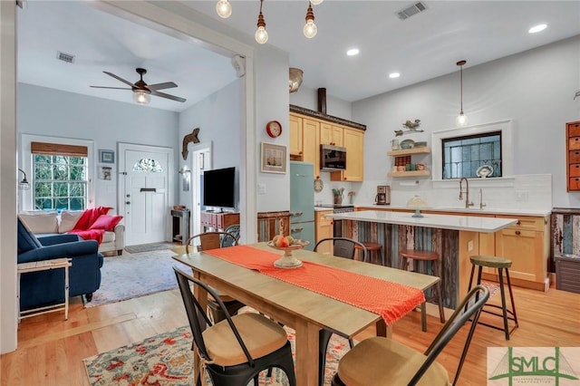 dining space with ceiling fan, light hardwood / wood-style flooring, and sink