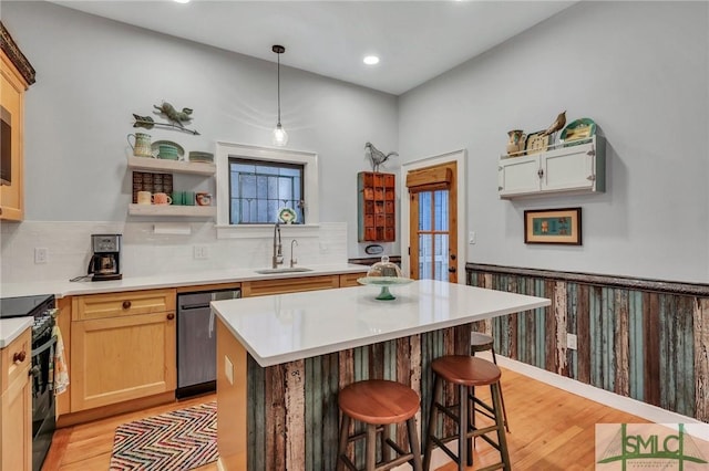 kitchen with a kitchen bar, stainless steel dishwasher, sink, decorative light fixtures, and black range