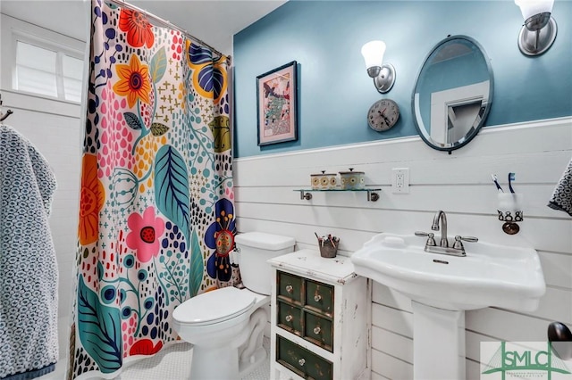 bathroom with a shower with curtain, toilet, and wood walls