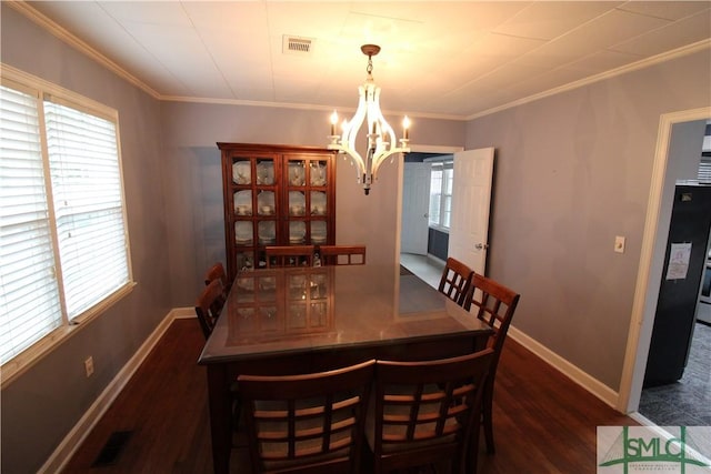 dining space featuring ornamental molding, an inviting chandelier, and dark wood-type flooring