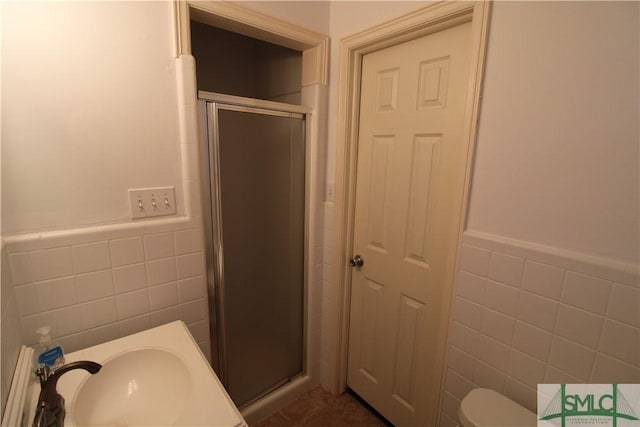 bathroom featuring walk in shower, toilet, tile walls, and sink