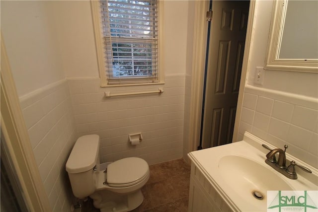 bathroom with tile patterned flooring, toilet, tile walls, and sink