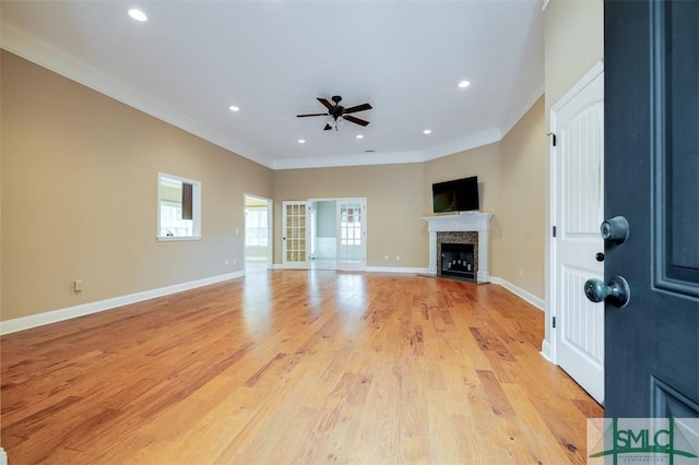 unfurnished living room featuring light hardwood / wood-style floors, ceiling fan, and crown molding