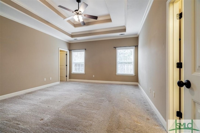 carpeted empty room featuring ceiling fan, a raised ceiling, and ornamental molding