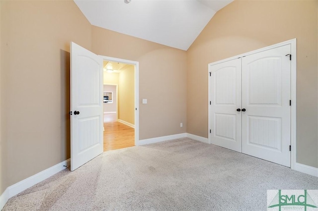 unfurnished bedroom with lofted ceiling, light carpet, and a closet