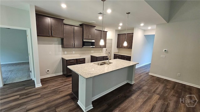 174 Brookline Dr, Savannah, GA 31407 - kitchen with stainless steel microwave, dark brown cabinetry, an island with sink, dark wood finished floors, and light countertops
