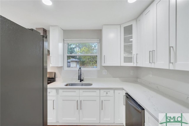 kitchen featuring white cabinets, stainless steel appliances, light stone counters, and sink