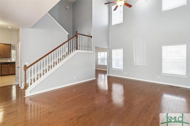 unfurnished living room with a high ceiling, dark hardwood / wood-style flooring, and ceiling fan