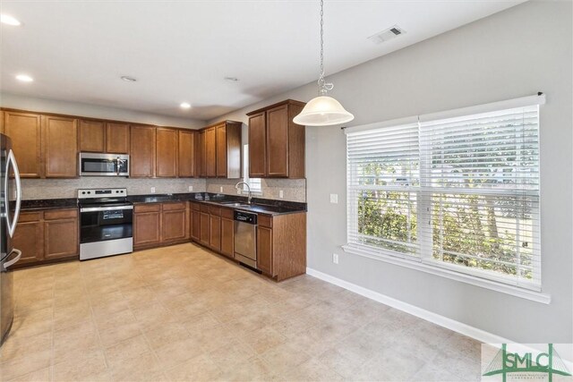 kitchen with a wealth of natural light, stainless steel appliances, hanging light fixtures, and sink