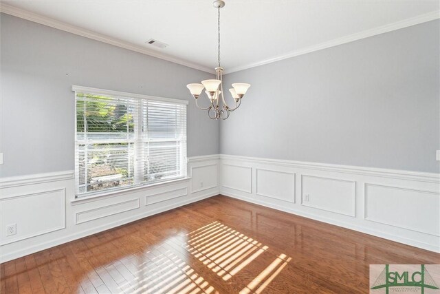 unfurnished room featuring crown molding, hardwood / wood-style floors, and a notable chandelier