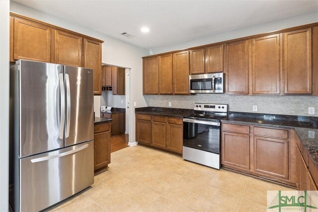 kitchen with decorative backsplash, stainless steel appliances, and dark stone counters