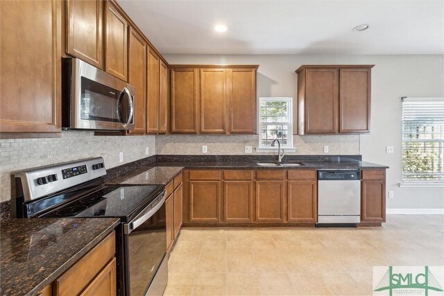 kitchen featuring sink, dark stone counters, and appliances with stainless steel finishes