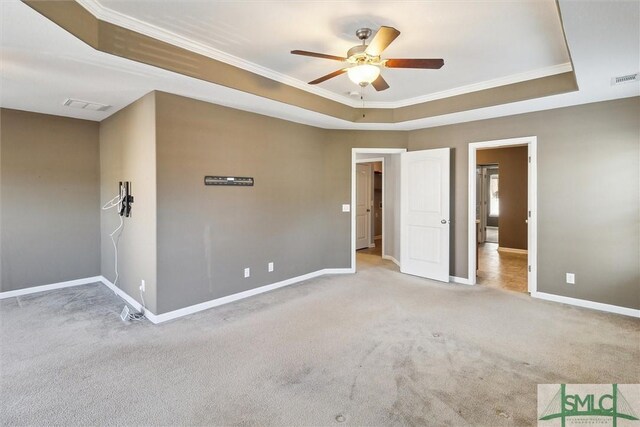 carpeted empty room with a tray ceiling, ceiling fan, and ornamental molding