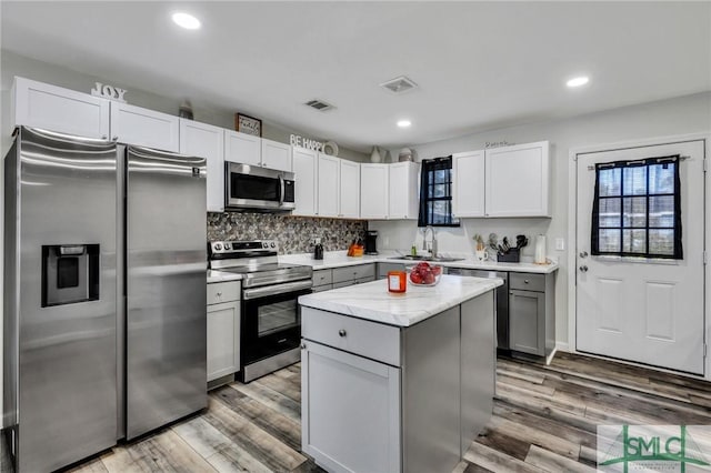 kitchen featuring gray cabinetry, white cabinetry, sink, stainless steel appliances, and a kitchen island