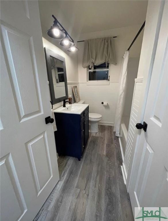 full bathroom with vanity, shower / tub combo with curtain, hardwood / wood-style flooring, tile walls, and toilet