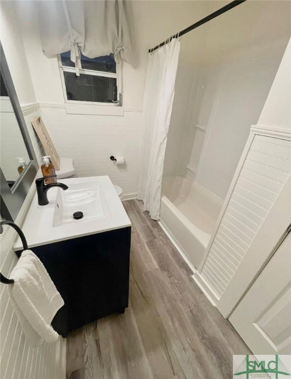 full bathroom featuring hardwood / wood-style floors, vanity, toilet, and shower / bathtub combination with curtain